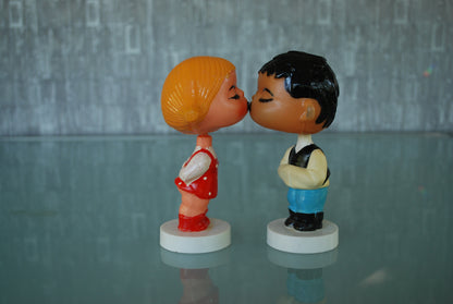 Kissing boy and girl bobblehead figures