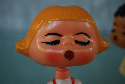 Kissing boy and girl bobblehead figures