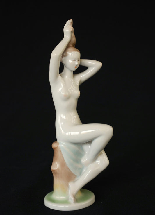 Naked woman on tree stump with blue towel