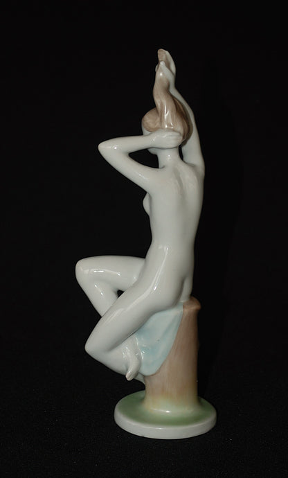 Naakte vrouw op boomstronk met blauwe handdoek