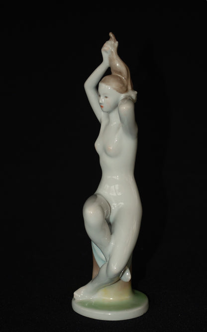 Naakte vrouw op boomstronk met blauwe handdoek