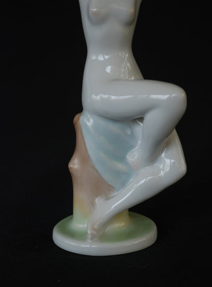 Naakte vrouw op boomstronk met blauwe handdoek